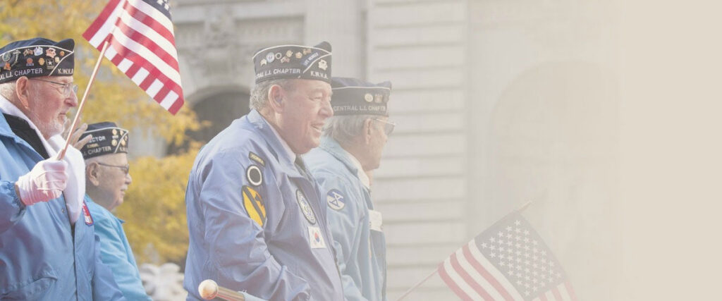 Veterans in service caps at a parade, carrying American flags