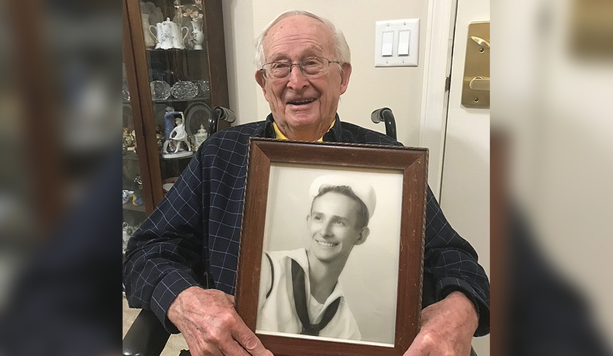 James E. Bryan holding a photo of himself from his time in the US Navy