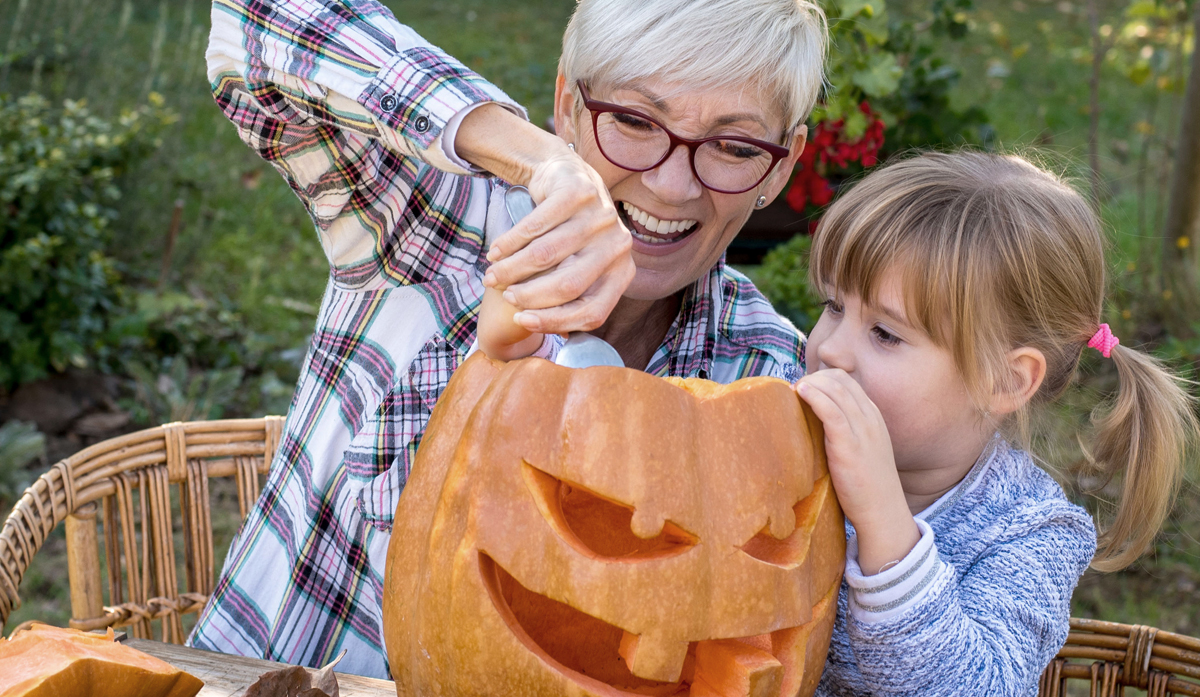 A Woman and her granddaughter working on a Halloween pumpkin together