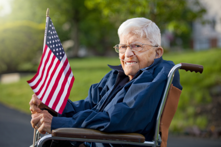 Smiling senior Veteran in a wheelchair holding a small American flag